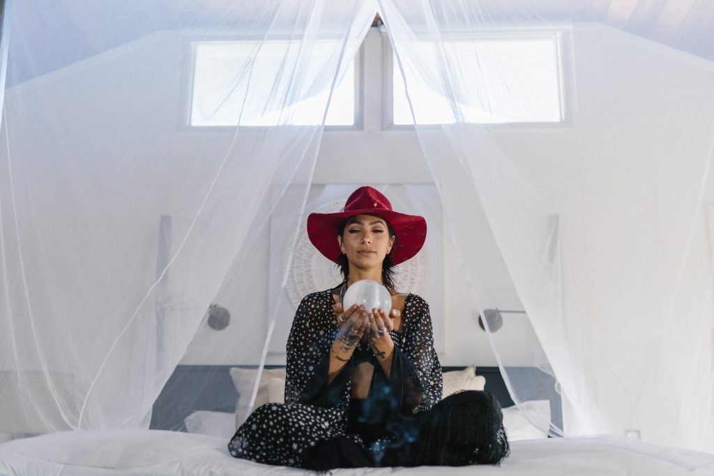 A woman sitting on a bed with a canopy holding a crystal ball to respresent the magic of SEO.